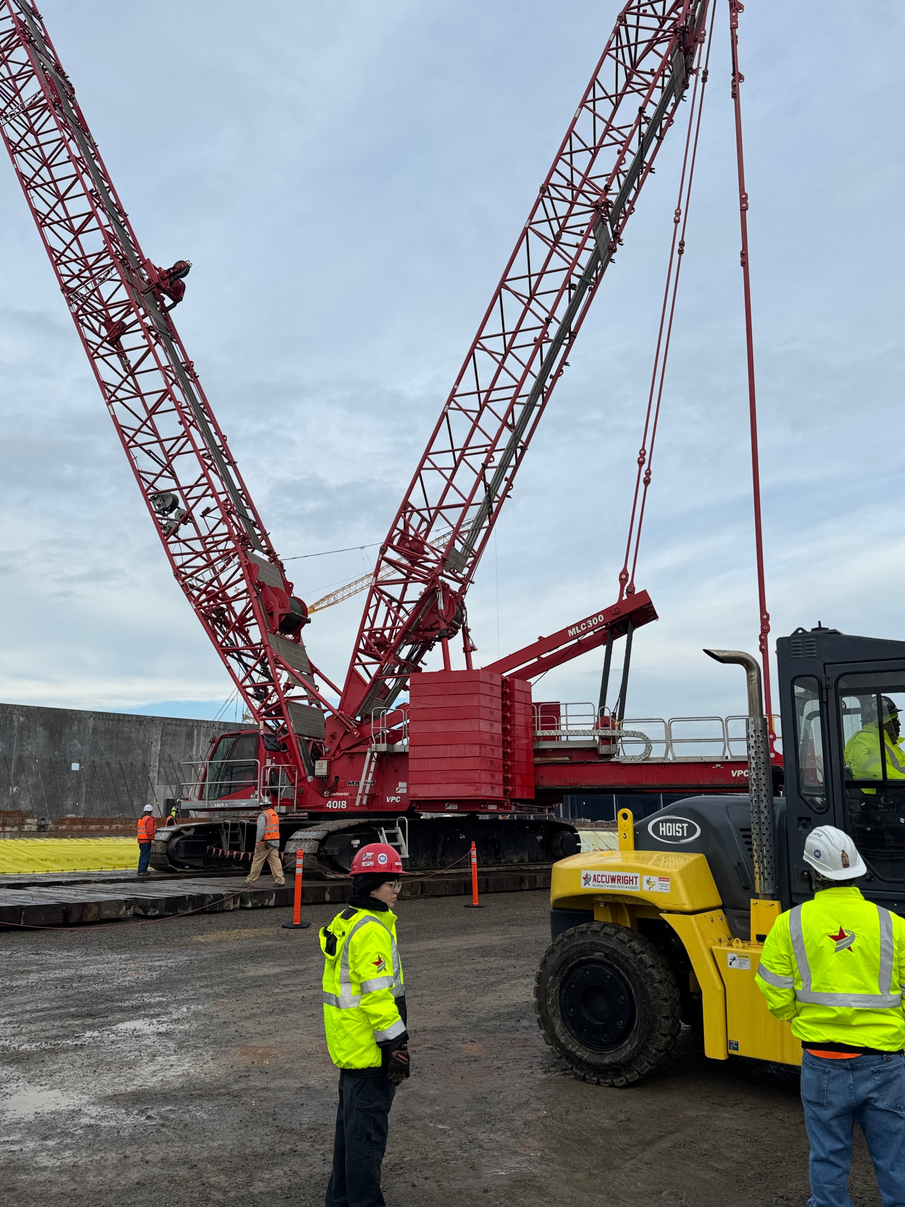 Accuwright crew with a heavy industrial forklift in front of crawler cranes