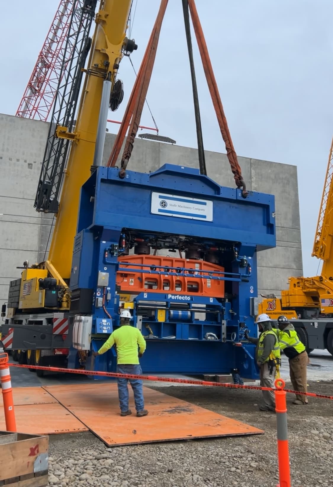 Accuwright rigging crew guiding a large industrial machine suspended from a crane