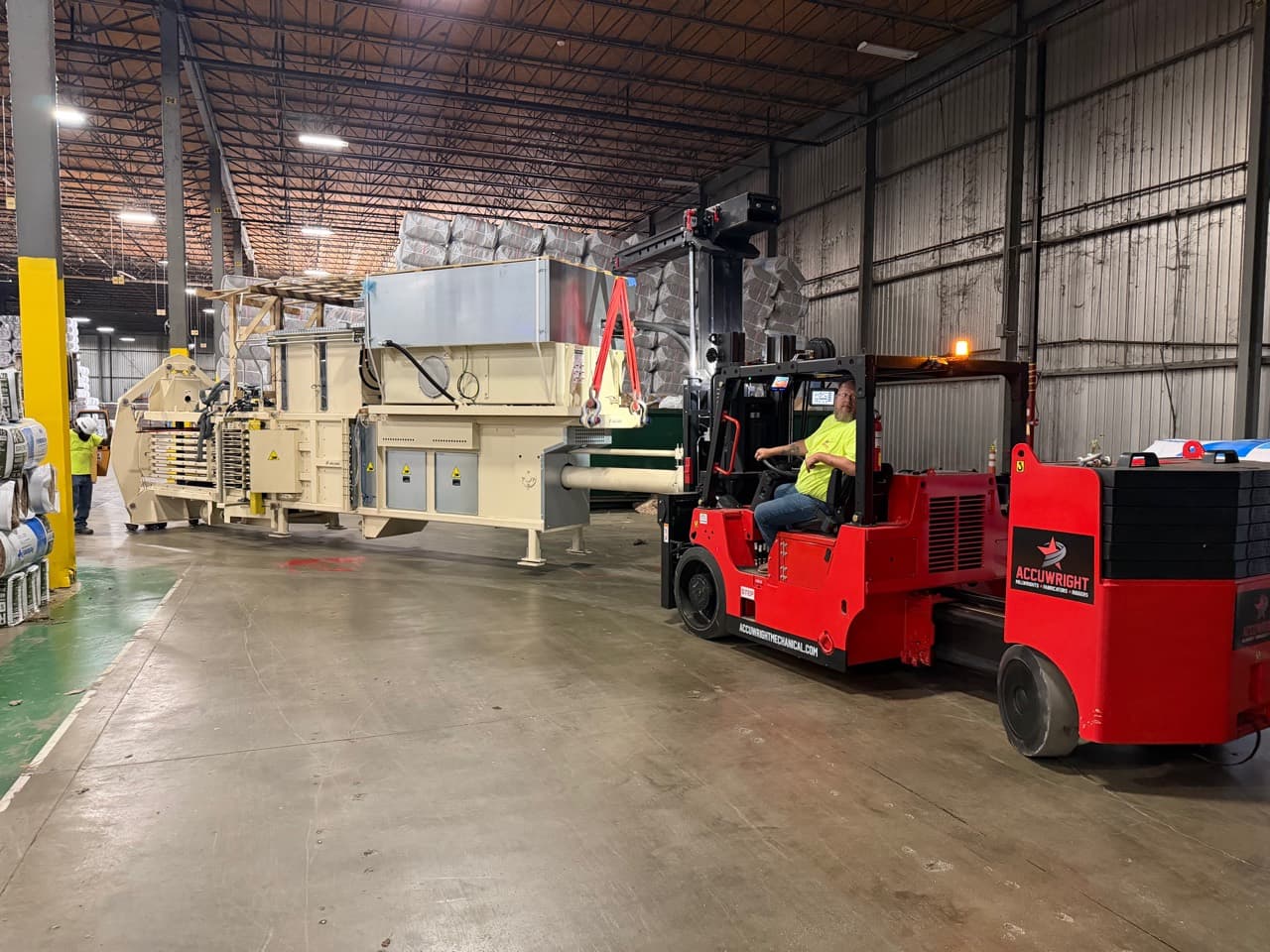 Indoor machinery rigging and installation Accuwright rigging crew positioning manufacturing equipment with a heavy forklift inside an industrial plant