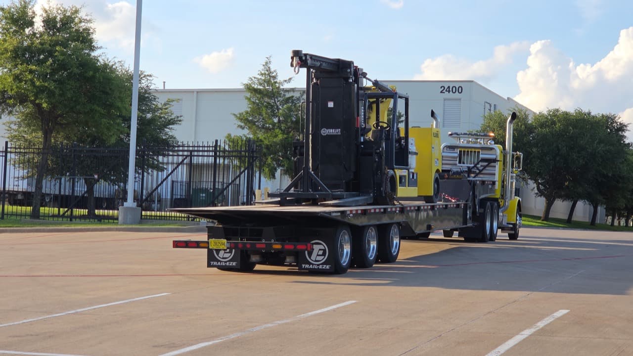 Industrial rigging forklift mobilization Industrial rigging forklift secured on a lowboy trailer for machinery moving and plant installation work